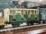 A green coach with a face owned by ThomasTankMerch on display at the Greenberg Train Show in 2022