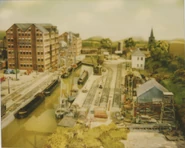 Two of the Shrimpers, the rail steam shovel and one of the Fire Station buildings on the set of Brendam Docks in a behind the scenes photo of the third series of Thomas & Friends.