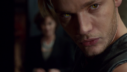 Jace's eyes turning gold while activating a rune on his arm.
