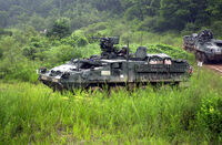 Two Strykers move through rough terrain in Korea