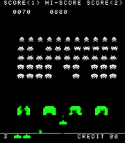 A vertical rectangular video game screenshot that is a digital representation of a battle between aliens and a laser cannon. The white aliens hover above four green, inverted U-shaped blocks. Below the blocks is a smaller horizontal block with a triangle on its top.