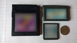 Clockwise from left: A  Game Pak, a  Game Pak, and a  Game Card. On the far right is a  shown for scale.