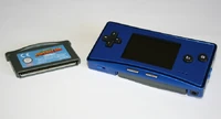 A blue Game Boy Micro next to a Game Boy Advance cartridge.