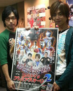 Takeshi Yoshioka and Taiyo Sugiura holding a poster for Ultraman Premier Stage 2