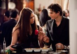 Damon dando a Elena uma rosa.