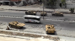 Ordlandic tanks and APCs on their way to the frontline on a major avenue in Elmira, Guetaso. A refugee bus passes by.