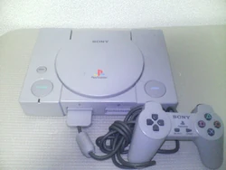 Una consola PlayStation con su mando de control.