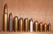 .45 Colt shown alongside other cartridges. From left to right: .30-06, 7.62×39 mm, .454 Casull, .45 Colt, .357 Magnum, .38 Special, .45 Auto, 9mm, .380, .22 Long Rifle