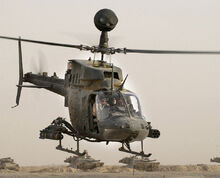 An OH-58 Kiowa showing its mast mounted sight and a rocket pod.