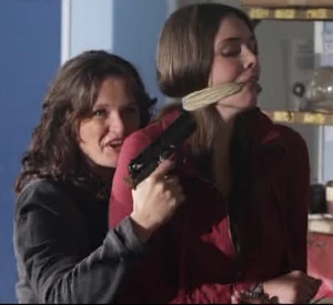 Audrey holding Fiona at gunpoint