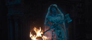 Constance guarding the fireplace, letting Crump's hat burn in the fire.