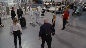 Poldark, Tatiana, and his henchmen gather around to witness the oil being eaten by the acid.