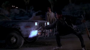 Charlie watching T. Paul shoot one of their car tires