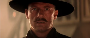 Van Cleef stares in disbelief after being shot in the chest by Roy.