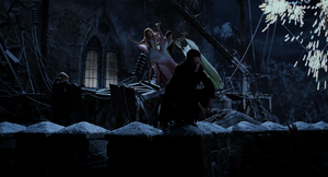 Dracula sits on the edge of the tower as the sobbing Brides cradle in their arms and Igor slithers up.