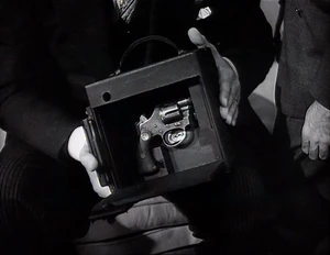 Grover planting a gun hidden in one of the cameras