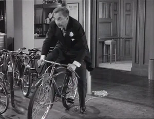 Grover riding a bike attached to a pole with a rope