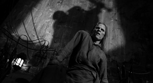 Up in the rafters, Igor sees Dracula kill Dr. Frankenstein and scurries off through a door, slamming it behind him.