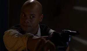 Walker holding Reid at gunpoint.