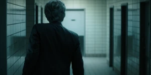 Brenner exiting out of the room after his men finish torturing One.