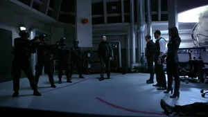 Garrett holding Coulson, May and Fitz at gunpoint.