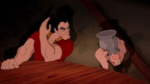 Gaston threatening to smack LeFou who cowers under his beer mug.