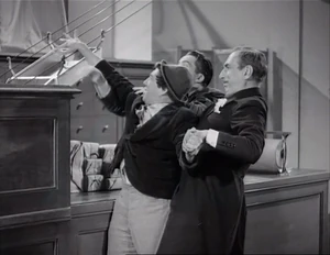 Grover and Duke restraining Ravelli just as he sends the picture up in a tray