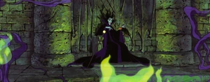 Maleficent sitting on her throne as her goons celebrate their victory around a bonfire.