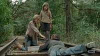 Lizzie attempts to let a walker bite her in order to show that they're not different from people. This is interrupted when a group of flaming walkers attack them.