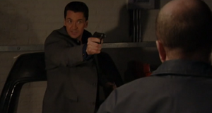 Phil is threatened at gunpoint by Dan as the latter demands the money (2001).