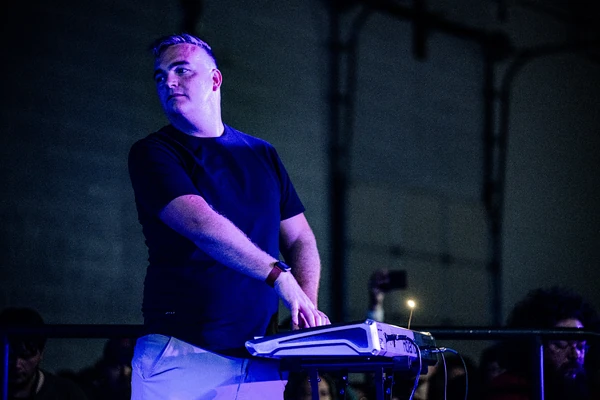 Bill playing the piano effortlessly while looking over to a band member.