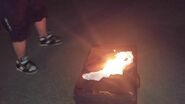 William puts a paper towel on top of the suitcase on fire