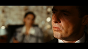 A picture of Mr. X in the foreground talking to Puja in the background
