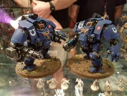 Two Redemptor Dreadnoughts of the Ultramarines Chapter displaying variant primary weapon load-outs; the left wields a Heavy Onslaught Gatling Cannon, the right a Macro Plasma Incinerator