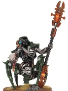 Illuminor Szeras in the process of analyzing an Aeldari's head; the mad Cryptek's altered Necron anatomy is clearly visible.