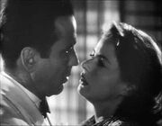 Black-and-white film screenshot of a man and woman as seen from the shoulders up. The two are close to each other as if about to kiss.