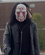 Джен, одетая в чёрный плащ, белую маску и чёрный парик, во время покушения на Нила Гэмби, финальная серия 1-го сезона.