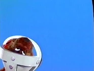 Puppet Wags in his astronaut helmet hanging upside down scratching