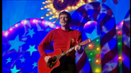 Murray playing his red Maton acoustic guitar in Santa's Rockin'! Live In Concert