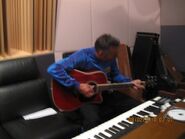 Anthony playing red Takamine acoustic guitar in Hot Potato Studios