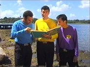 The Non-realistic Wiggles looking at a book about Captain Feathersword