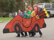 The Wiggles in the Big Red Car outside waving