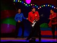 Murray playing his red Maton electric guitar in "LIVE Hot Potatoes!"