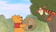 Winnie the Pooh hands over the paper beehive to Tigger