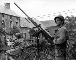 Group of French citizens gather outside a house under watch of an M2HB machine gun, Normandy 1944