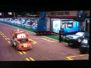 Mater driving past a pit row, which uses Dinoco oil.