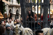 Logain grins up through the bars of his cage during the procession