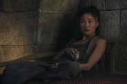 Episode 202: Min leans back on a stone wall with a drink