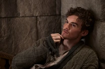 Episode 202: Mat leans back on a stone wall looking thoughtful