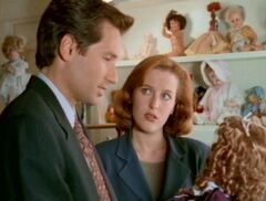 Dana Scully watches Fox Mulder holding a doll